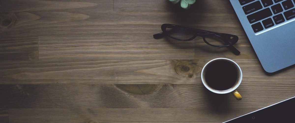 Un PC, des lunettes, une tasse de thé sur une table : un client recherchant des agences immobilières digitales