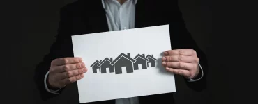 Un agent immobilier tenant une photo de maison : loi Hoguet immobilier