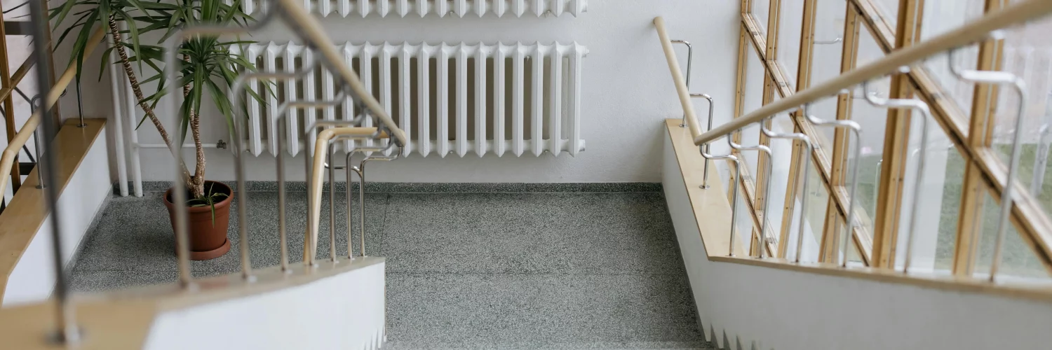 Un escalier dans un immeuble collectif avec un radiateur en face