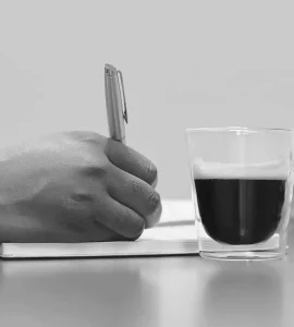 Un notaire qui prend des notes avec une tasse de café à coté.