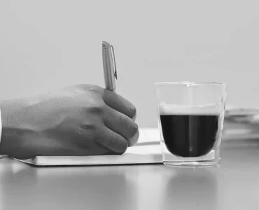 Un notaire qui prend des notes avec une tasse de café à coté.