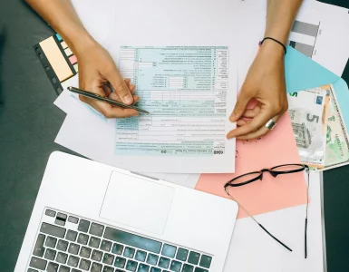 une jeune femme vérifiant ses déclarations fiscales devant un PC