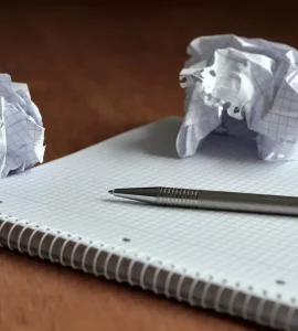 Papiers fracassés, un cahier et un stylo sur une table