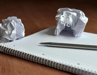 Papiers fracassés, un cahier et un stylo sur une table