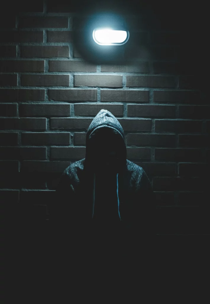 Un voleur au visage caché devant un mur en brique